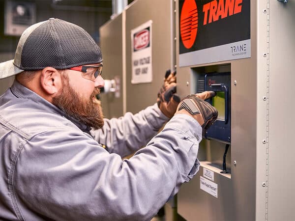 Person working on an open Trane HVAC unit.